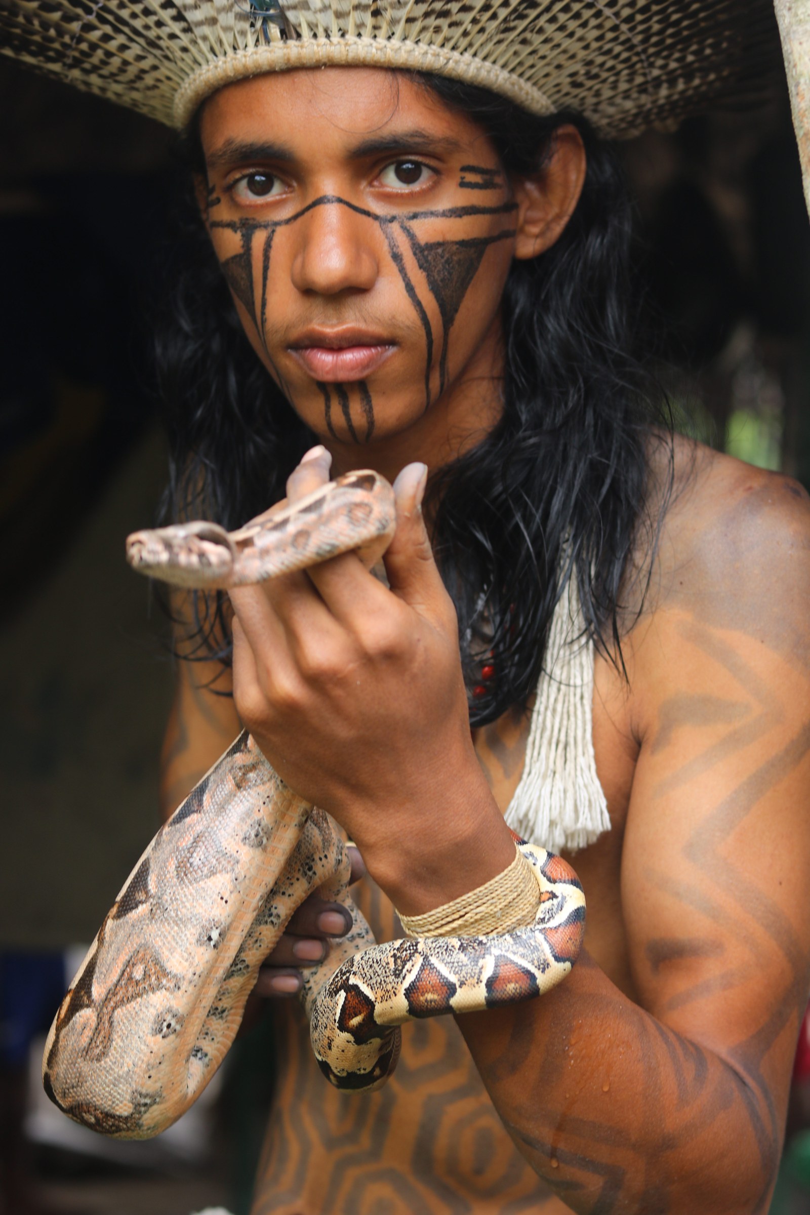 Retrato de integrante Kariri-Xocó com pintura corporal e serpentes